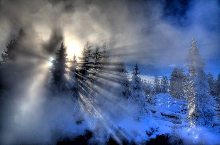 The winter sun fights to get shine through steam and fog at a frigid Yellowstone.
