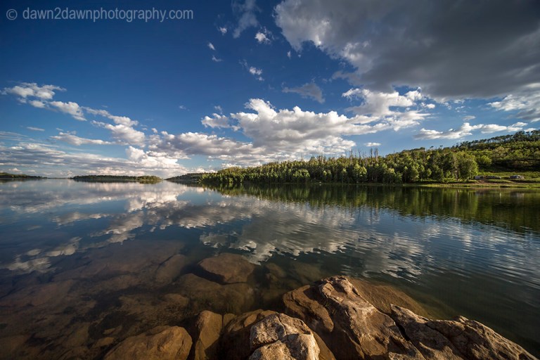 Passing clouds are reflected in the still waters of Kolob Reservoir near Zion National Park, Utah