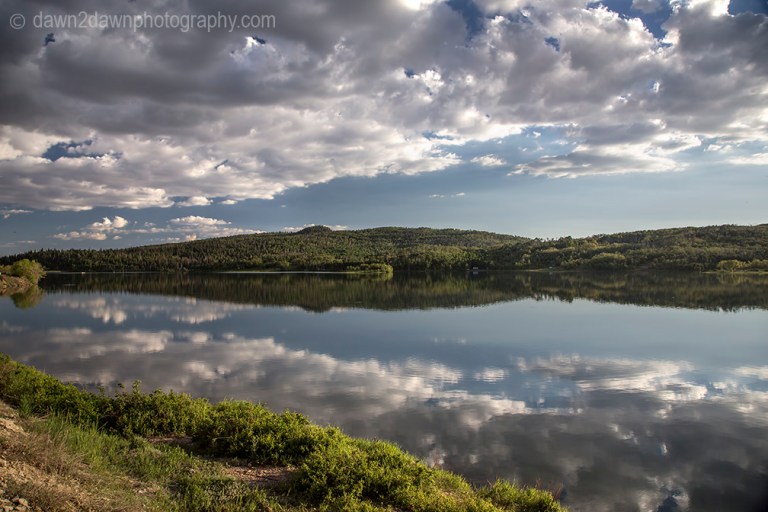 Passing clouds are reflected in the still waters of Kolob Reservoir near Zion National Park, Utah