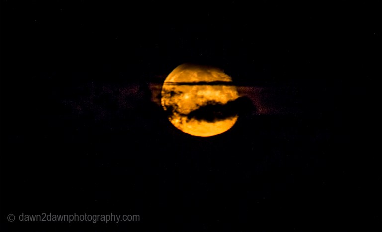 A full moon rises amongst soem passing clouds in Northern Arizona