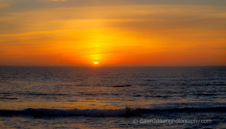 The sun sets over the Pacific Ocean near San Simeon, California