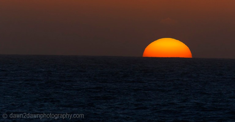 The sun sets over the Pacific Ocean at San Simeon, California