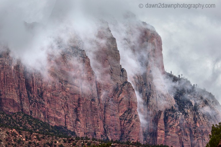 A passing thunderstorm deposits clouds around Mount Kinesava at Zion National Park, Utah