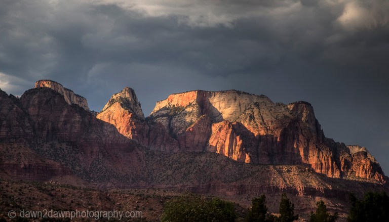 The light from the setting sun shines on the West Temple at Zion National Park, Utah