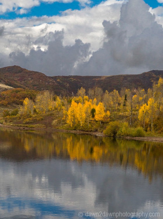 Fall colors from Aspen trees are reflected in the still waters of Kolob Reservoir near Zion National Park, Utah