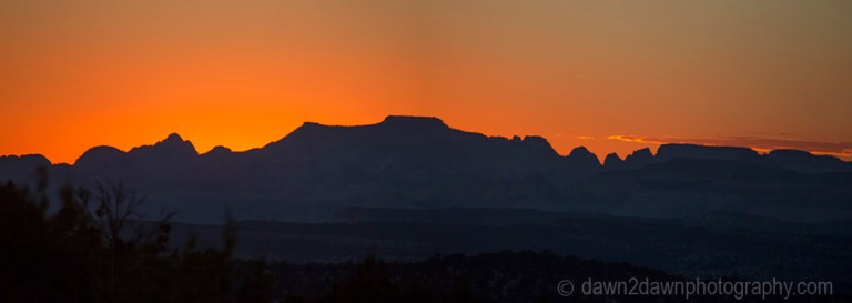 The sun sets behind the skyline of Zion National park, Utah