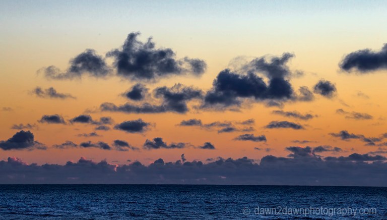 The light from the setting sun casts a soft light on clouds over the Pacific Ocean at California's central coast.