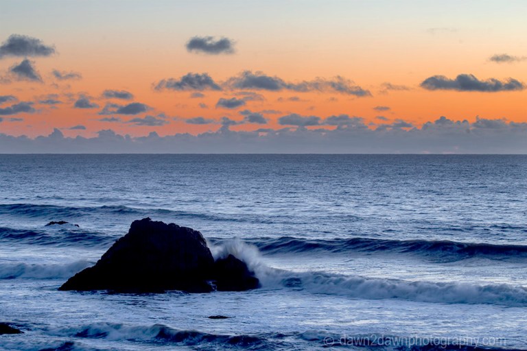 The light from the setting sun casts a soft light on clouds over the Pacific Ocean at California's central coast.