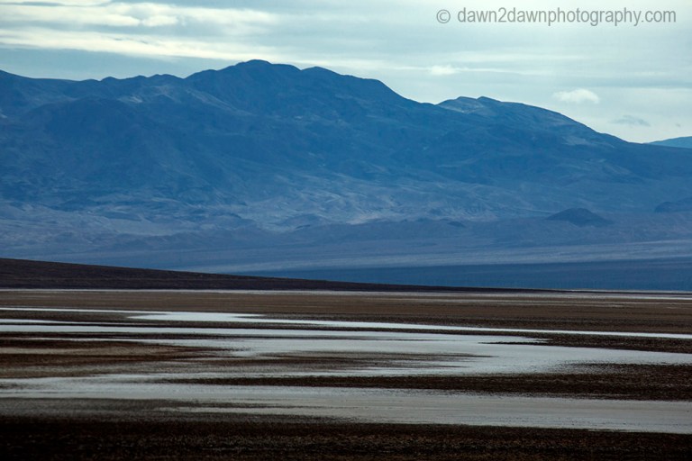 Passing storm clouds filter sunlight on the landscape at Badwater Basin at Death Valley National Park, California