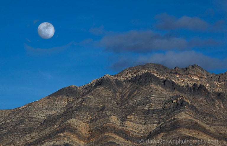 A nearly full moon rises over the Last Chance Mountains at Death Valley National Park, California
