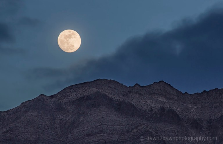 A nearly full moon rises over the Last Chance Mountains at Death Valley National Park, California