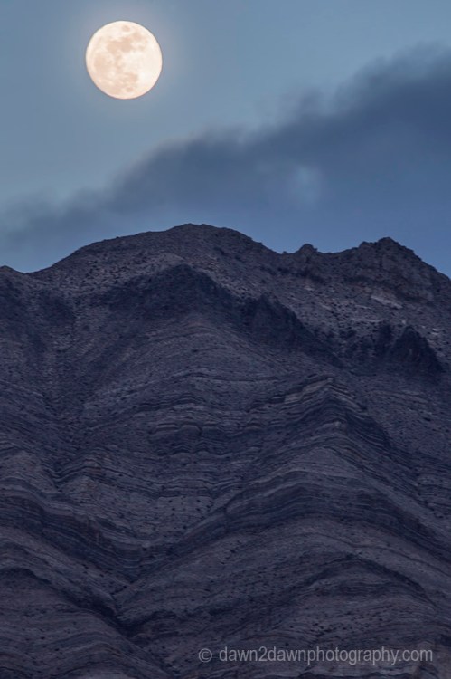 A nearly full moon rises over the Last Chance Mountains at Death Valley National Park, California
