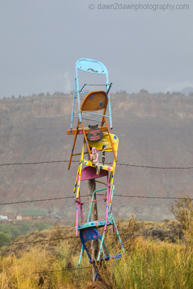 Chairs Stacked On A Barbed-Wire Fence
